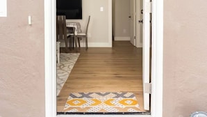 Una puerta que da a una habitación con una mesa de comedor y sillas, un televisor y una alfombra estampada.