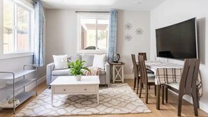 Una sala de estar con sofá, mesa de centro, televisor y comedor.