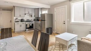 Una cocina moderna con gabinetes grises, un refrigerador de acero inoxidable y un comedor con mesa y sillas.