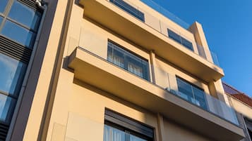A multi-story building with balconies, large windows, and a clear blue sky.