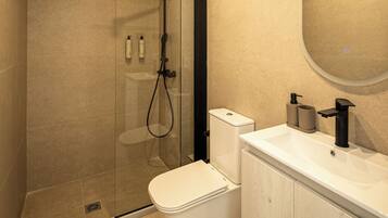 Une salle de bain moderne avec une douche à parois de verre, des toilettes et un lavabo avec un miroir.