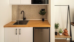 A compact kitchen with white cabinets, a stainless steel sink, a built-in oven, and a compact dishwasher. - Ormos Piraeus (Piraeus)