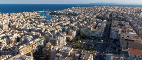 A coastal cityscape with dense urban buildings, a marina, and a clear view of the sea.