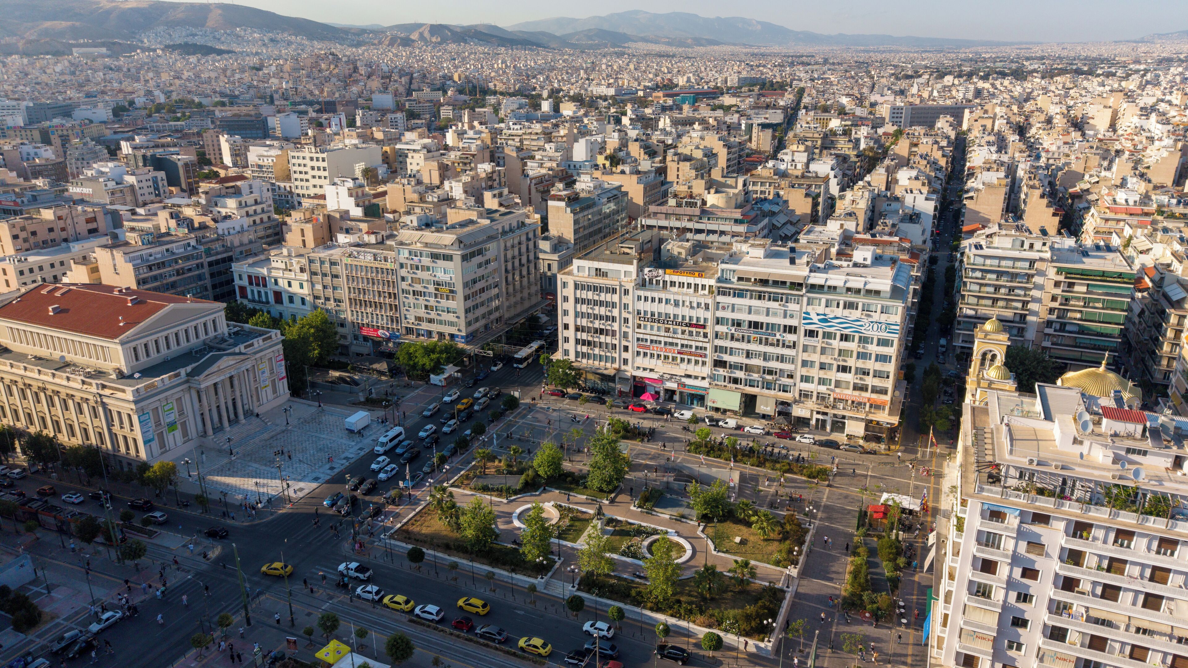 A cityscape with a prominent building featuring a large sign, a busy intersection, and surrounding urban buildings.