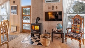 L’intérieur d’un chalet accueillant, avec un poêle à bois, une télévision, un globe terrestre et un fauteuil agrémenté d’un coussin à motifs.