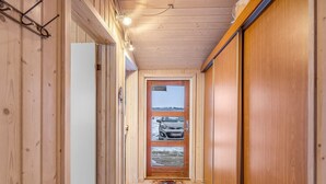Un couloir étroit en bois, avec une porte donnant sur un garage.