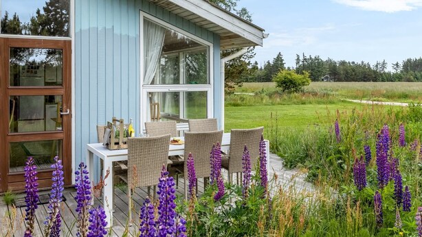 Une maison avec une terrasse, une table à manger et des chaises.