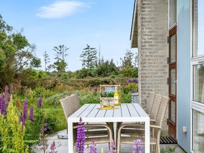 A wooden table with wicker chairs, a bottle, and a menu in a garden setting. - "Gebko" - 750m from the sea by Interhome (Løkken)
