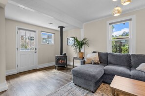 Ein Wohnzimmer mit grauem Ecksofa, einem Holztisch, einem Kamin und einem großen Fenster mit Blick.