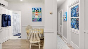 A hallway with a dining area, featuring a wooden table and chairs, a painting on the wall, and a patterned rug. - Phoenix Nest - Downtown Apartment in Belfast (Belfast)