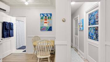 Un couloir comprenant un coin repas, avec une table et des chaises en bois, un tableau au mur et un tapis à motifs.