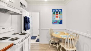 A compact kitchen with a stove, chairs, and a dining table. - Phoenix Nest - Downtown Apartment in Belfast (Belfast)