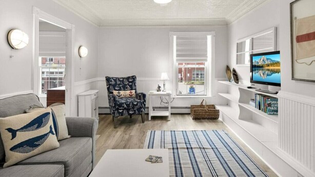 A living room with a sofa, armchair, TV, bookshelf, and a window with blinds. - Phoenix Nest - Downtown Apartment in Belfast (Belfast)