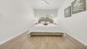 A bedroom with a bed, a ceiling fan, a window with blinds, and two wall-mounted lamps. - OneLuxStay Coastal 2BR Near Beach (Torrance)