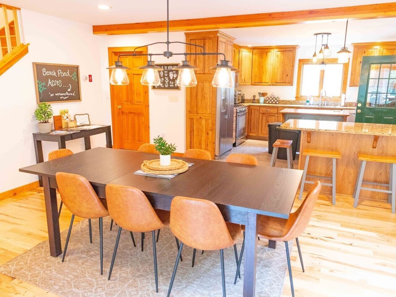 A dining area with a large table, chairs, and pendant lighting.