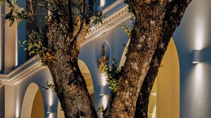A building facade with a central statue, arched doorways, and a tree in the foreground. - Royal Nidri Suites (Nidri)