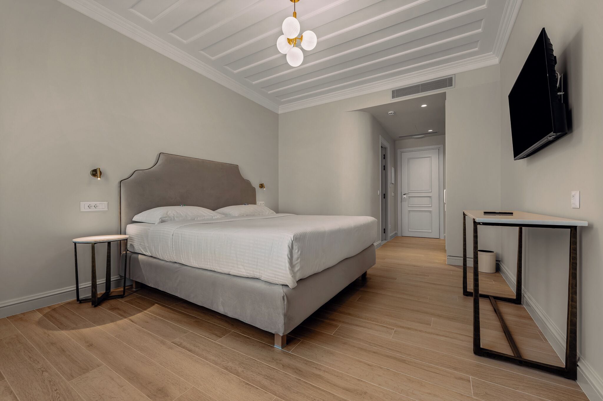 Un dormitorio con cama, mesitas de noche, televisor y lámpara en el techo.