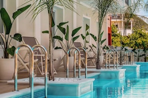 A pool area with multiple sun loungers and metal poolside railings.