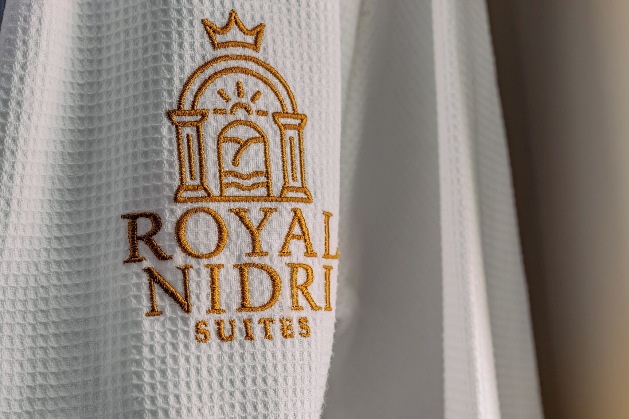 Une serviette ornée d’une broderie avec le texte « ROYAL NIDRI SUITES » et d’une illustration représentant un bâtiment.