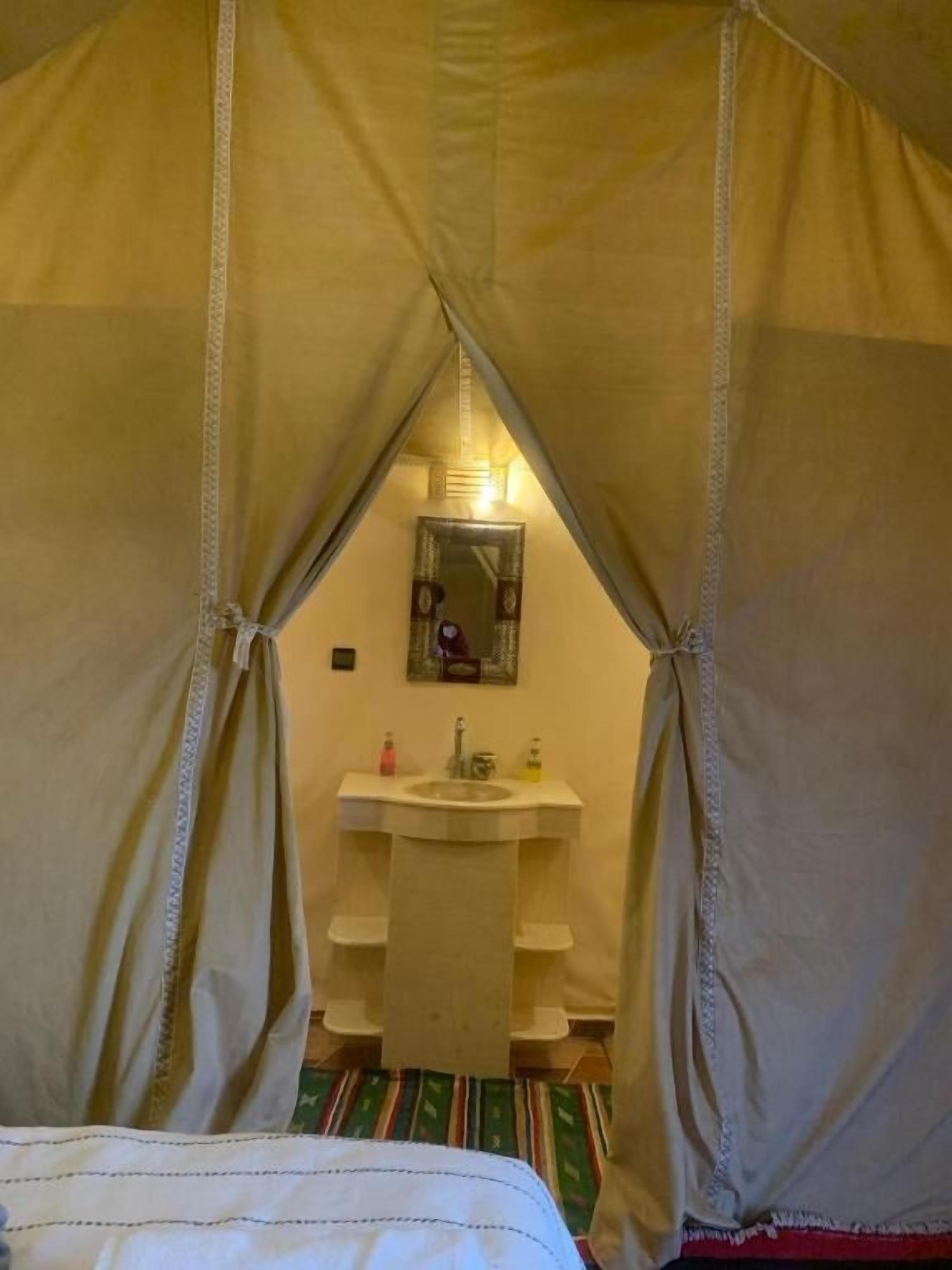 Een kamer met een bed, een klein wastafeltje en een spiegel.