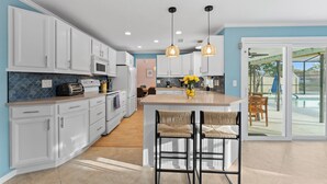 Una cocina moderna con armarios blancos, una isla central e iluminación colgante.