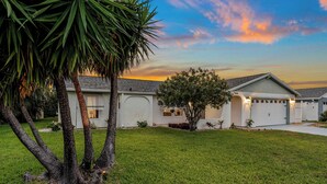 Una casa residencial con fachada blanca, un garaje y un césped bien cuidado.
