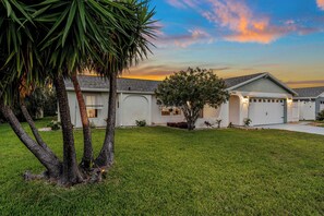 Una casa residencial con fachada blanca, un garaje y un césped bien cuidado.