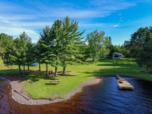 A lakeside property with a dock, picnic table, and a small cabin.