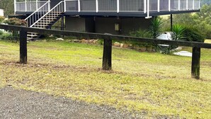Ein zweigeschossiges Haus mit einer Veranda, einer Satellitenschüssel und einer Treppe, die zu der oberen Etage führt.