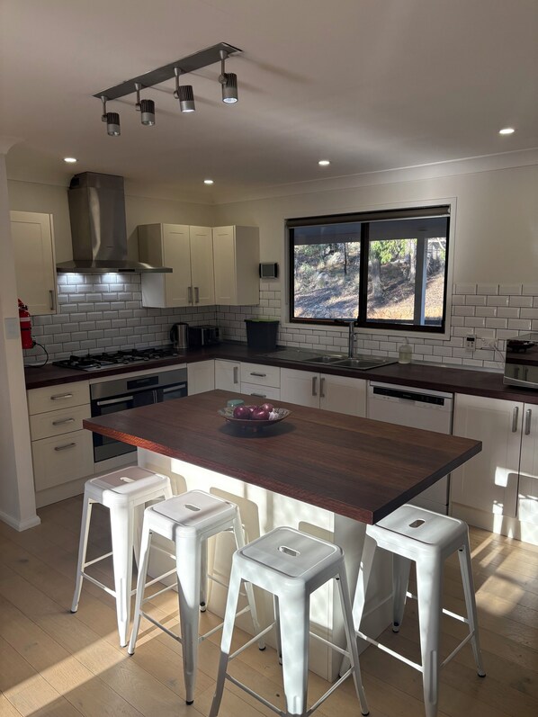 A modern kitchen with a central island, white cabinetry, and a large window.