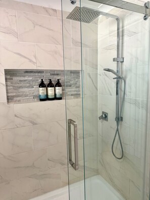 Een douche met glazen wand, een handdouche en een wandmengkraan.