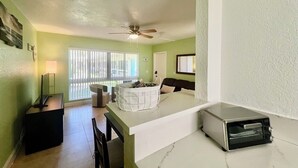 A modern kitchen with a built-in oven, a dining area with a table and chairs, and a large window with blinds.
