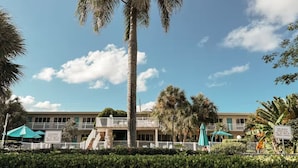 A hotel with a central building, surrounded by palm trees and a clear sky.