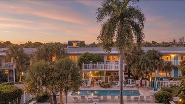 A resort with a pool, multiple buildings, and palm trees.