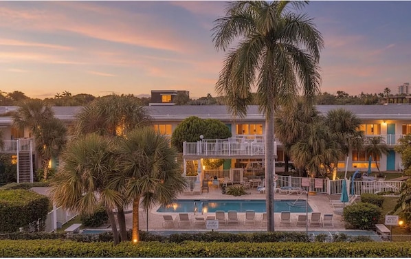 Un resort con piscina, varias edificaciones y palmeras.