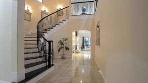 Un hall d’entrée spacieux avec un escalier en colimaçon, une plante en pot et une vue sur l’espace de vie.