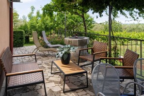 Eine Außenpatio mit Steinböden, Lounge-Stühlen, einem Tisch und einem Grill.