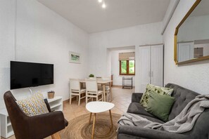 Ein Wohnzimmer mit Fernseher, Sofa und Essbereich.