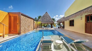 A swimming pool with lounge chairs, a thatched-roof structure, and a view of the sea. - Quinta Ixchel -3 Luxury Sac Bajo Beachfront Villas - Private Beach, Pool and... (Isla Mujeres)