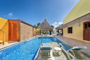 A swimming pool with lounge chairs, a thatched-roof structure, and a view of the sea. - Quinta Ixchel -3 Luxury Sac Bajo Beachfront Villas - Private Beach, Pool and... (Isla Mujeres)