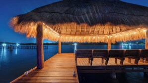 A wooden deck leading to a thatched-roof structure with seating, overlooking a calm body of water. - Quinta Ixchel -3 Luxury Sac Bajo Beachfront Villas - Private Beach, Pool and... (Isla Mujeres)