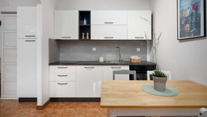 Eine moderne Küche mit weißen Schränken, einer schwarzen Arbeitsplatte und einem Holzesstisch mit einem Blumentopf.
