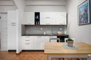 Eine moderne Küche mit weißen Schränken, einer schwarzen Arbeitsplatte und einem Holzesstisch mit einem Blumentopf.