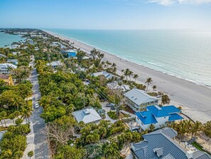 Luftaufnahme einer Küstenwohngegend mit Häusern, einer Straße und einem Strand.