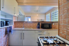 A kitchen with a stove, sink, microwave, and coffee maker.