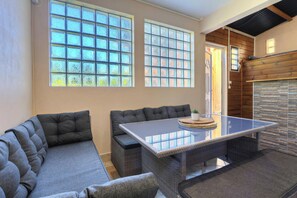 A room with a sofa, a table, and large windows with patterned glass.