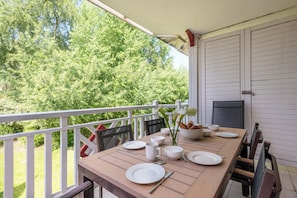 Ein Esstisch im Freien mit weißen Tellern, Schüsseln und einer Blumenvase.