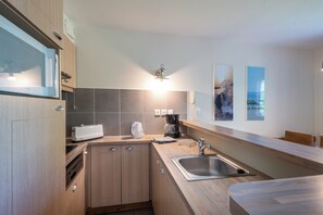 Eine moderne Küche mit Holzausstattung, einer eingebauten Mikrowelle, einer Kaffeemaschine und einem Spülbecken.