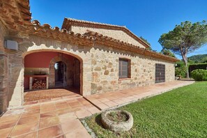 Un edificio de piedra con techo de tejas, un arco de entrada y una ventana pequeña.