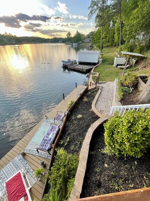 Uma propriedade à beira do lago com um píer, cadeiras de descanso e um jardim bem cuidado.